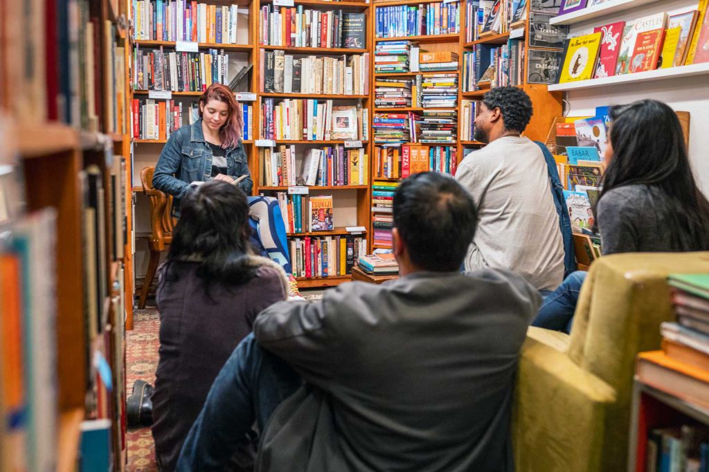 A woman reading to a group inside a bookstore..