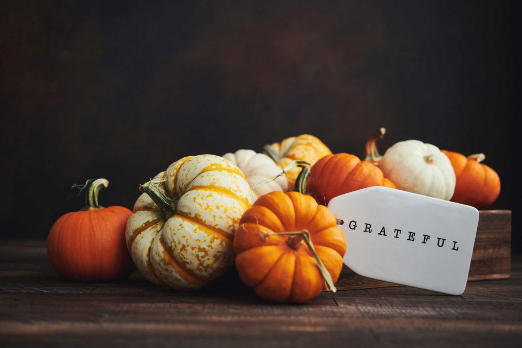 Close up of a centerpiece of small pumpkins and squash with a tag that reads "Grateful."