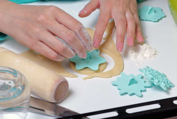 Close up on a woman's hands using a snowflake cookie cutter on some salt dough.